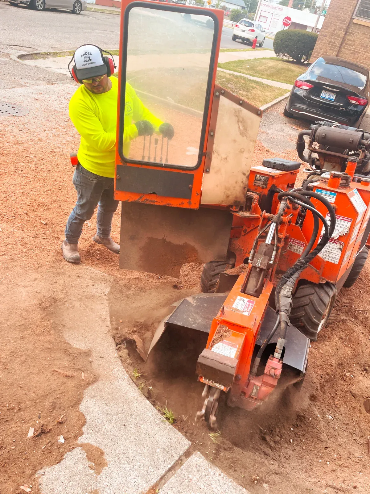 Operator grinding a stump next to a driveway